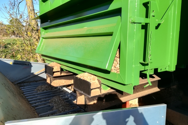 Gros plan sur le container-silo amovible. Le fond mouvant pousse les plaquettes, qui tombent dans une trémie et sont directement amenées dans la partie « stock tampon » de 10 m³ du container chaufferie